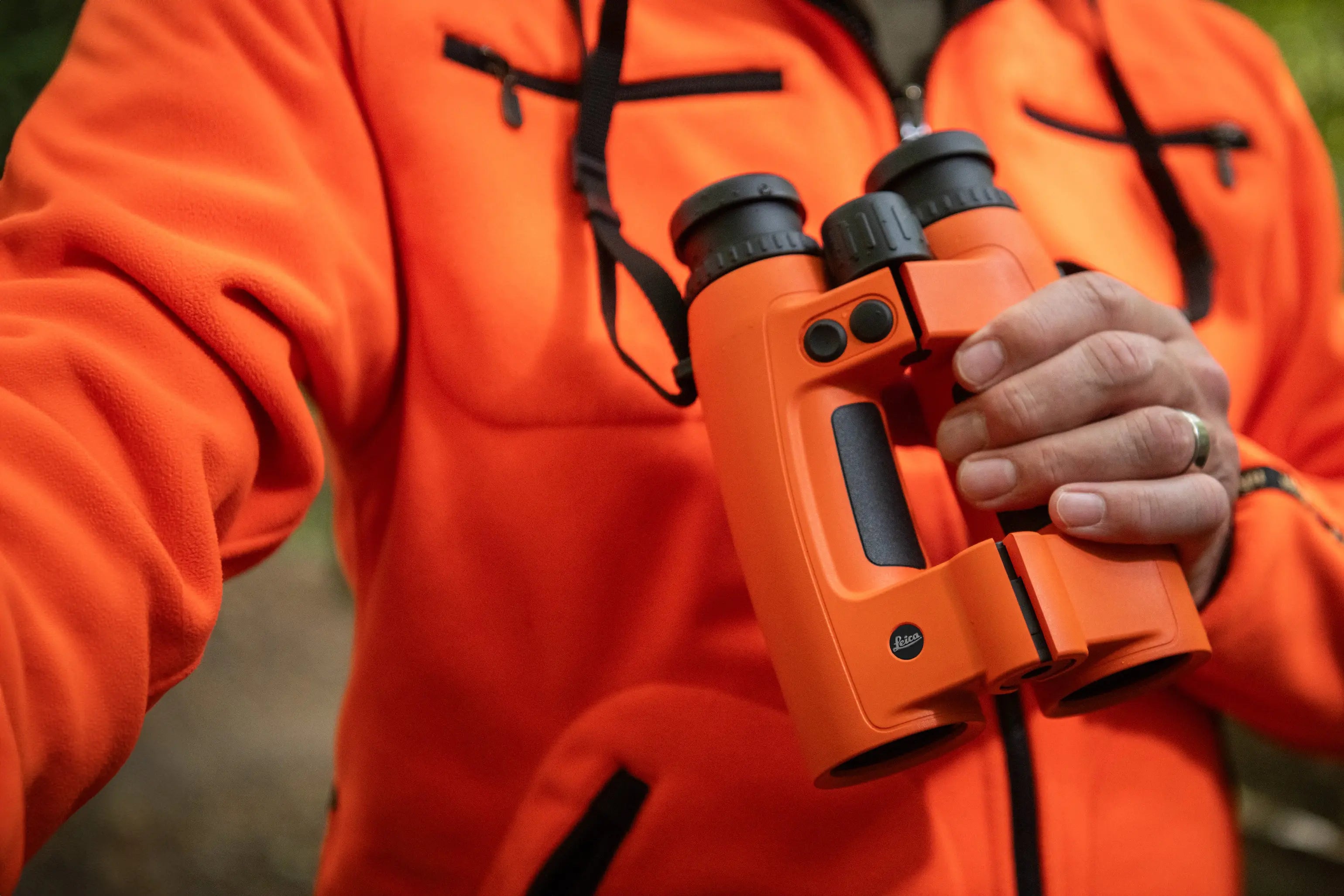Person wearing an orange jacket holding orange binoculars.